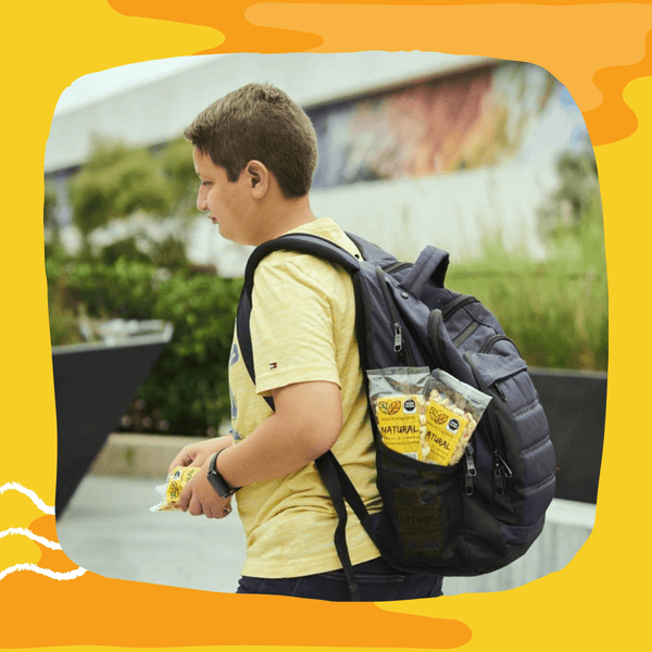 Niño con mochila camino a la escuela comiendo maicitos inflados blofis sabor natural