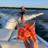 Bolsa de chips de vegetales en una lancha frente a una persona en wakeboard
