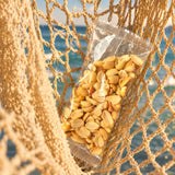 Bolsa de 50 g de cacahuate natural Blofis colgada en una red de pesca frente al mar