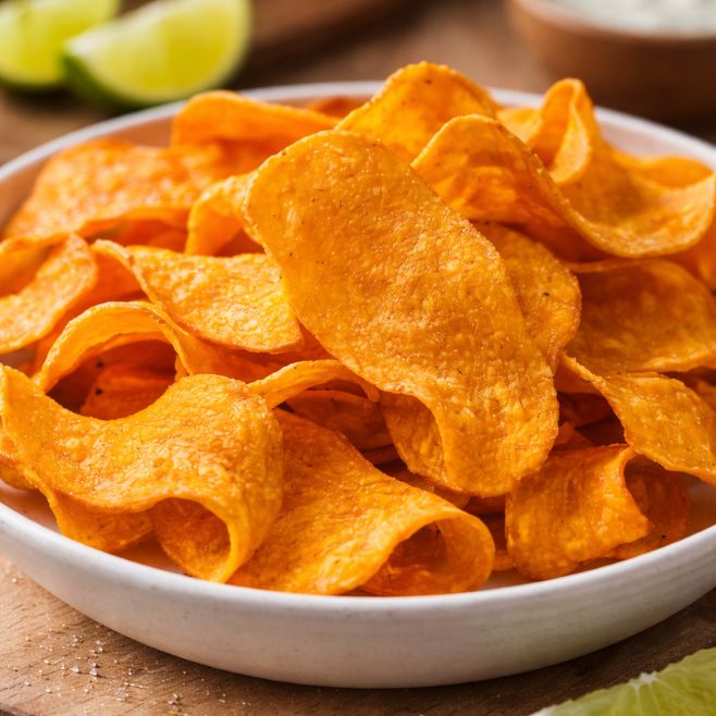 plato extendido con chips de camote sabor limon sobre mesa de madera en bar