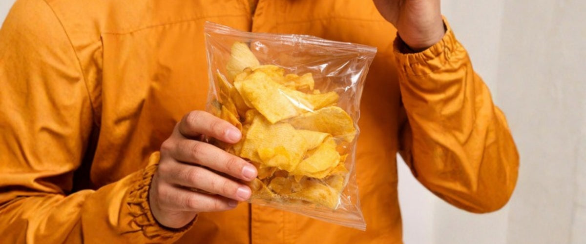 Persona con chamarra naranja sosteniendo una bolsa de chips de jícama Limón y Sal