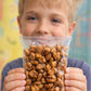 niño de primaria sosteniendo una botana saludable de maiz inflado al vapor sabor salsas negras dentro de su colegio
