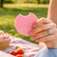 obleas de amaranto sabor frutos rojos con una pequeña mordida, fondo de parque verde con mantel de picnic