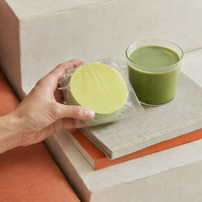 paquete de obleas de amaranto sabor matcha sobre unos libros de literatura y a un lado un matcha helado contexto habitación minimalista