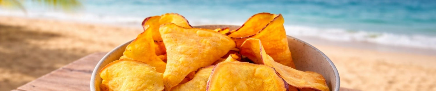 chips de camote sabor limon sobre mesa de madera con vista a la arena y mar, botana para vacaciones